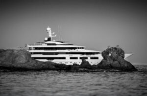Large yacht partially seen behind rocks