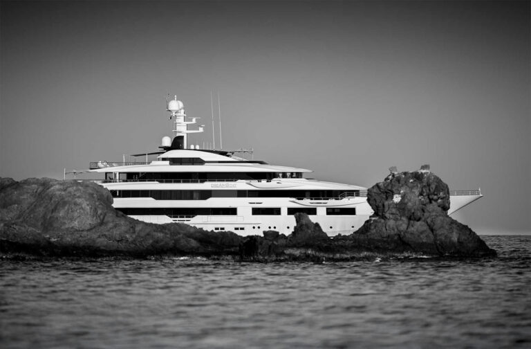 Large yacht partially seen behind rocks
