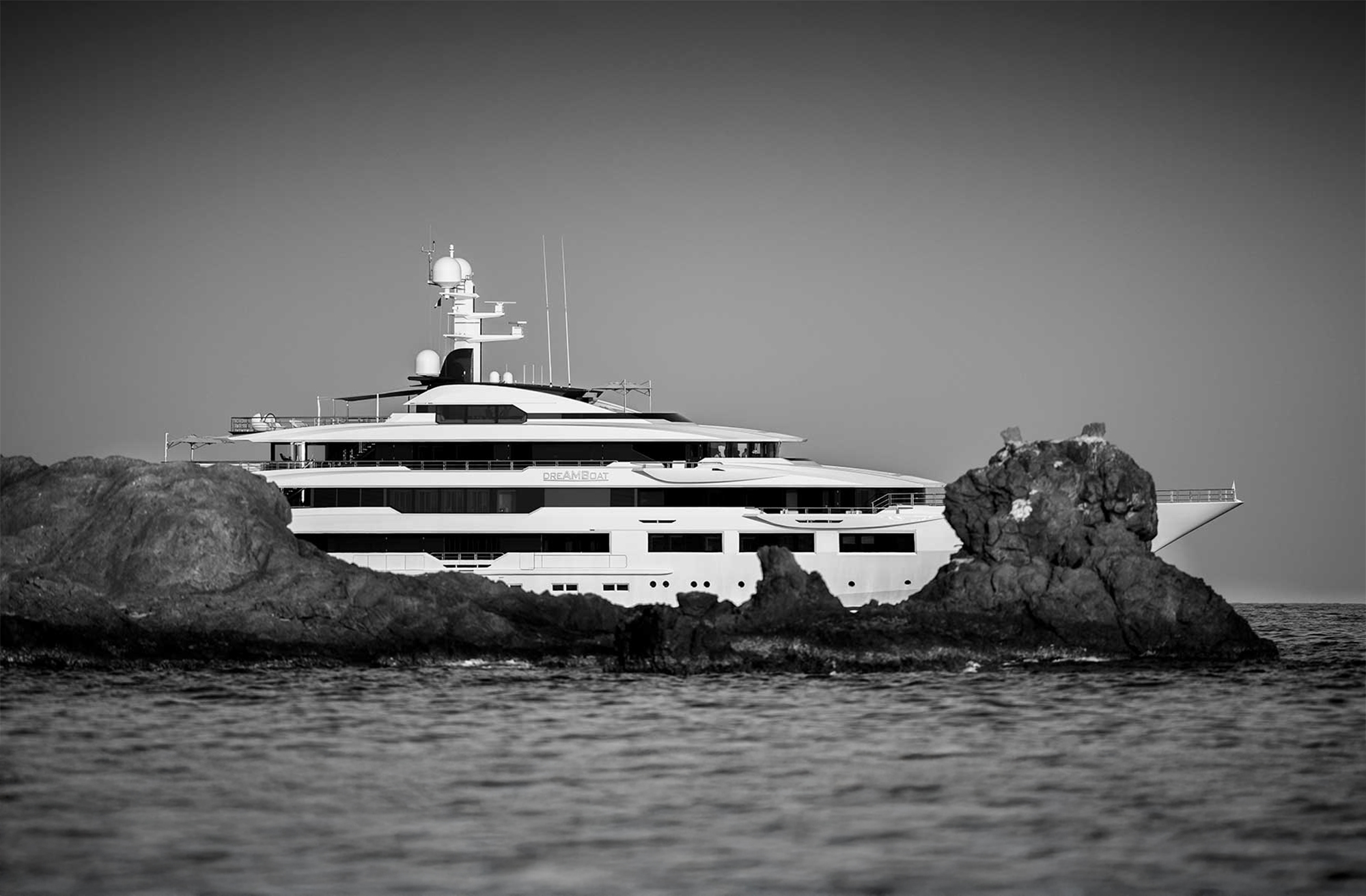 Large yacht partially seen behind rocks
