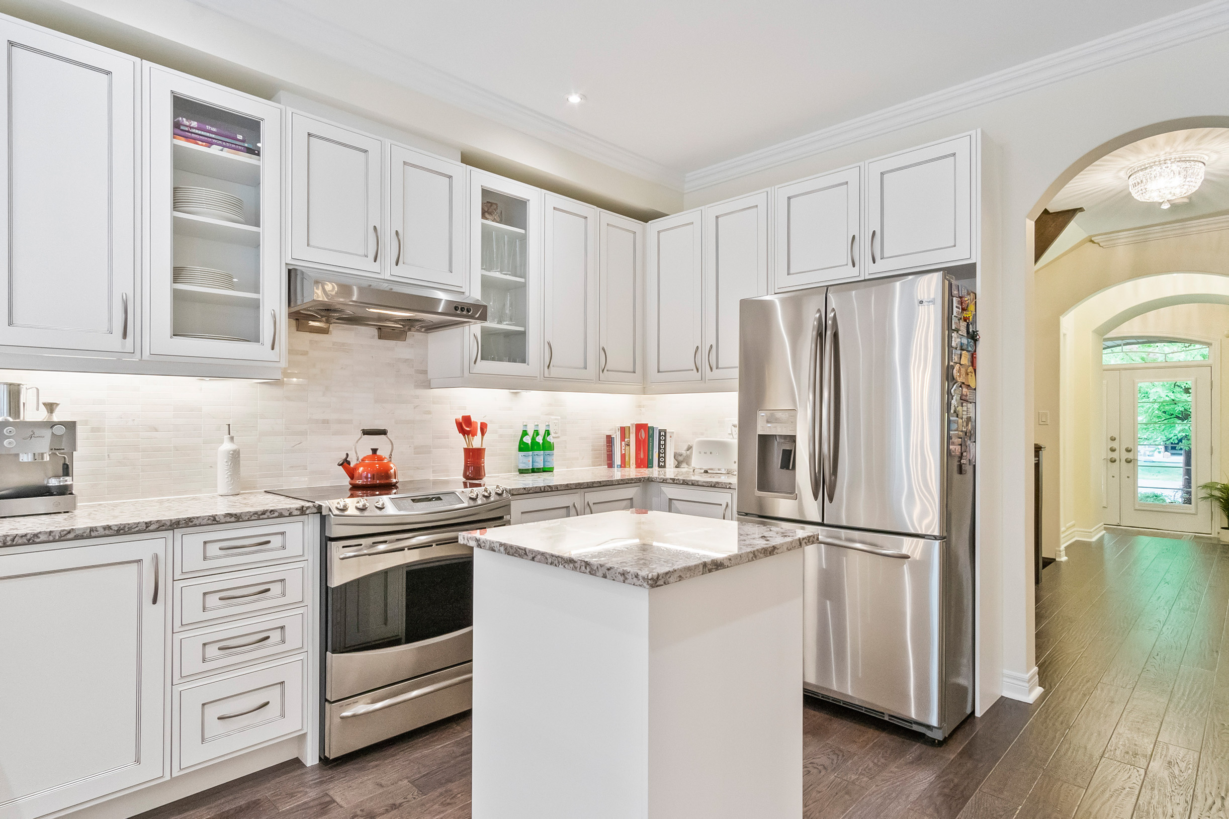 Modern kitchen with white cabinets, stainless steel appliances, and a central island