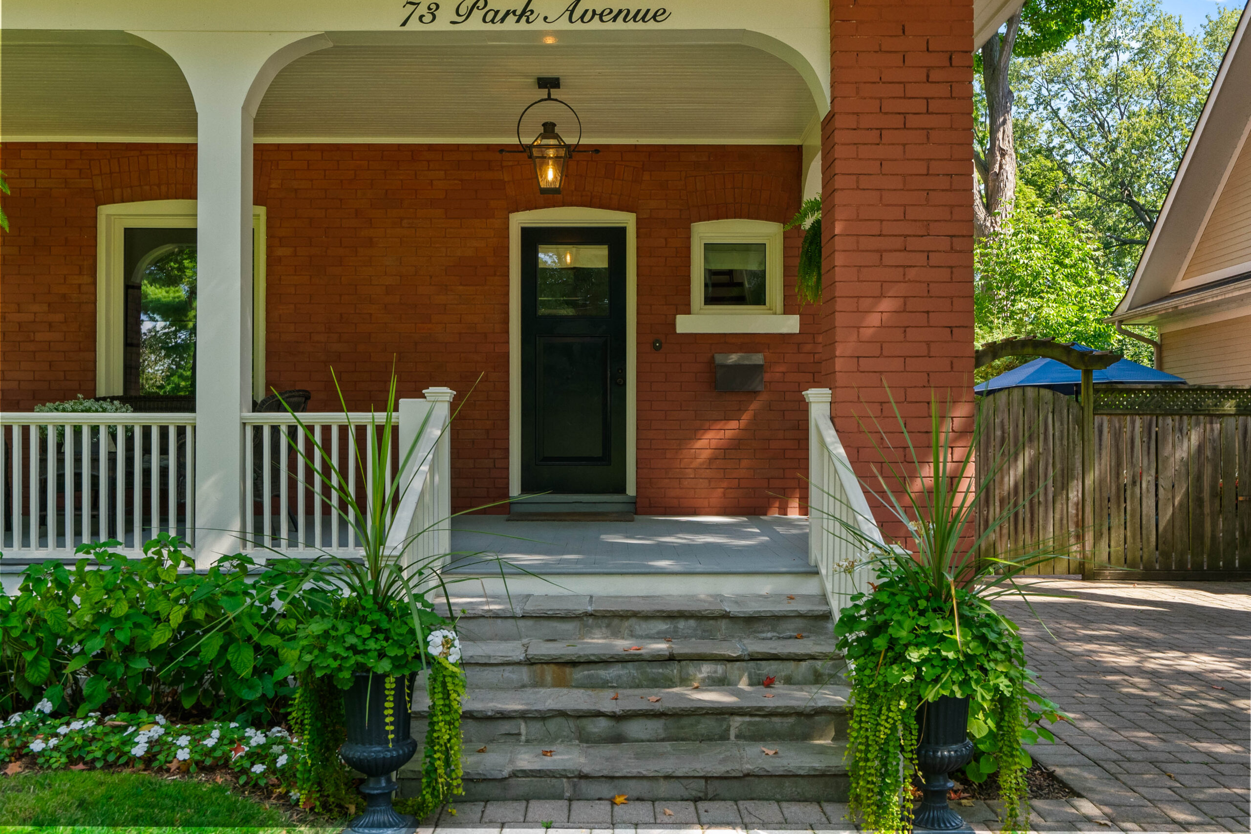 Front porch of a brick house with steps and potted plants