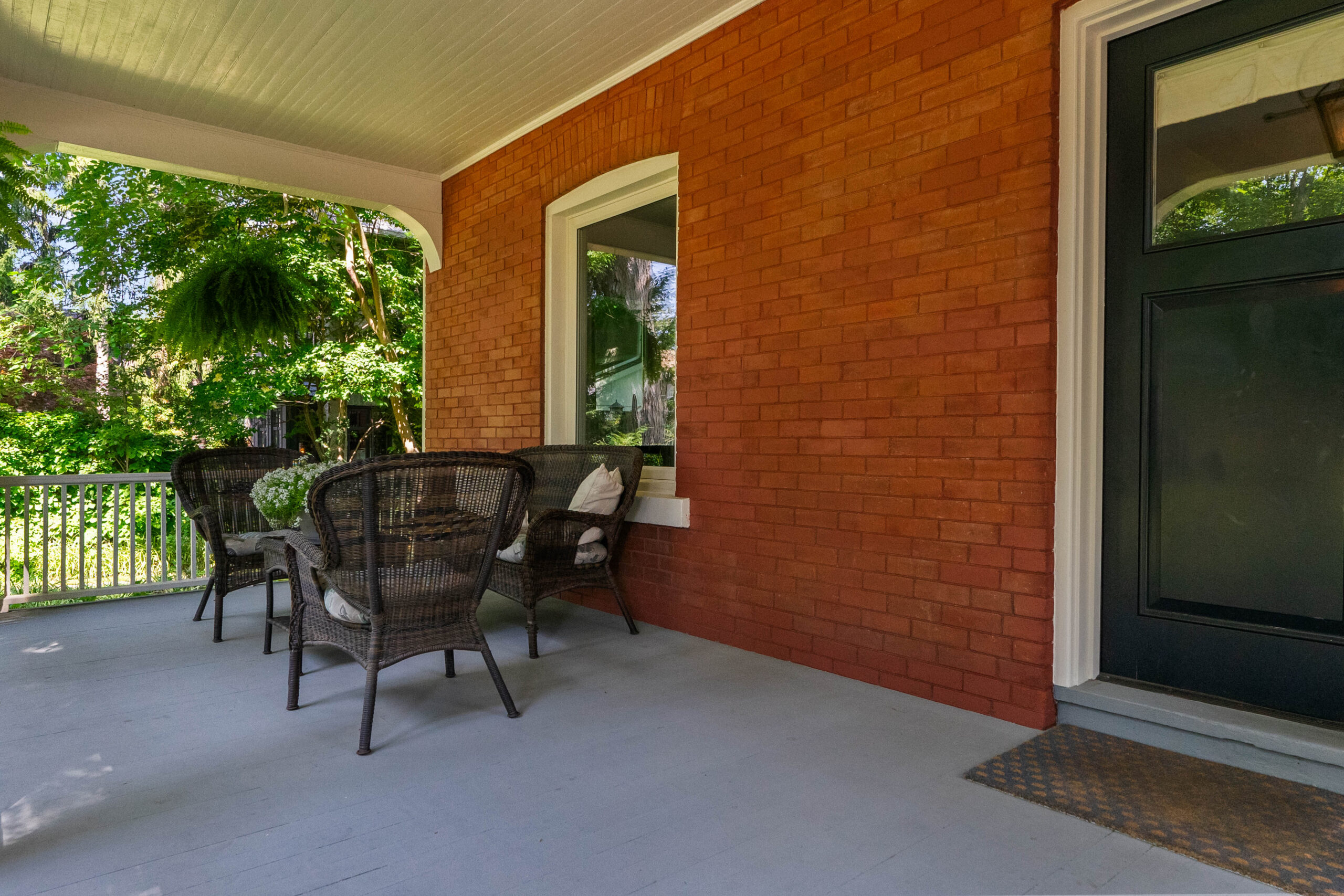 Cozy porch with wicker chairs and a green door against a brick wall
