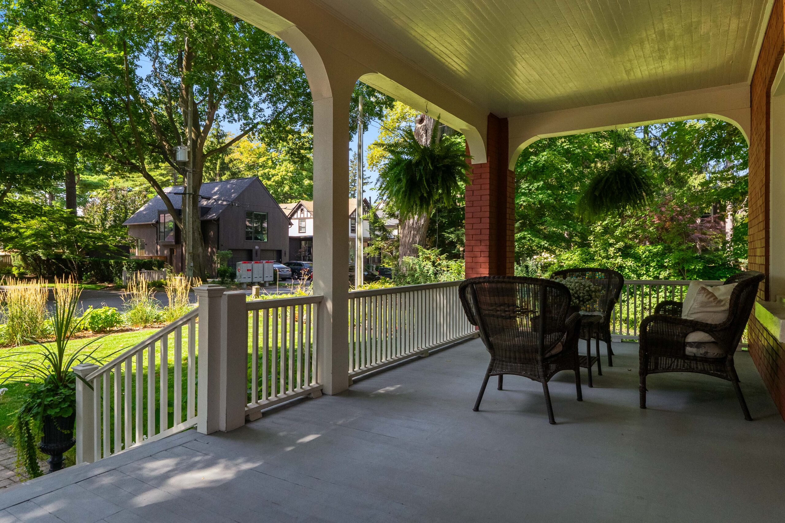 Cozy porch with wicker chairs overlooking a lush garden and trees