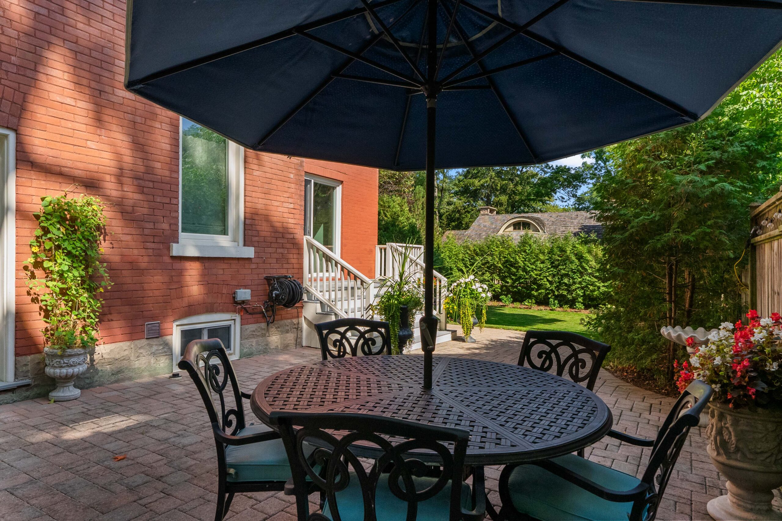 Patio with a round table, chairs, and a large umbrella in a garden setting