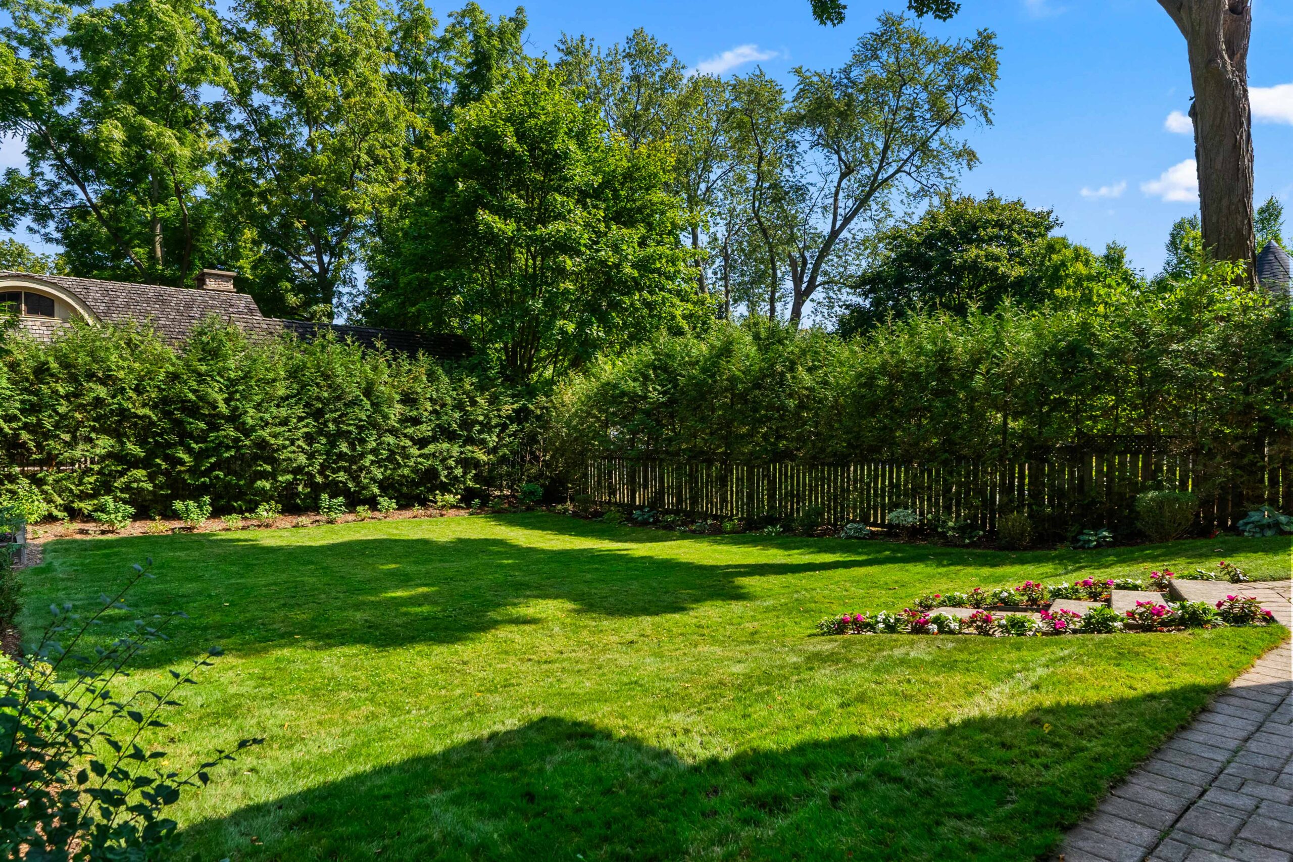 Lush green backyard with neatly trimmed grass and flower beds