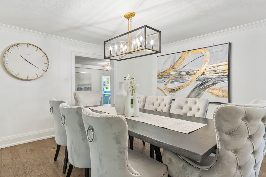 Elegant dining room with a gray table, tufted chairs, and modern chandelier.