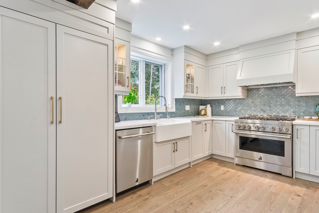 Modern kitchen with white cabinets, stainless steel appliances, and a large window