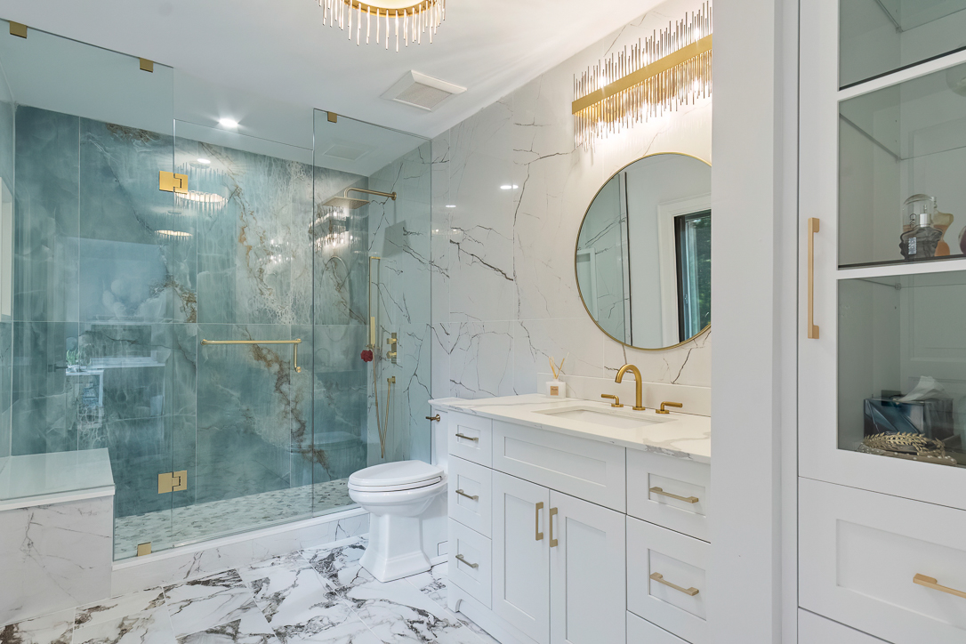 Luxurious bathroom featuring marble tiles, gold accents, and a glass shower enclosure