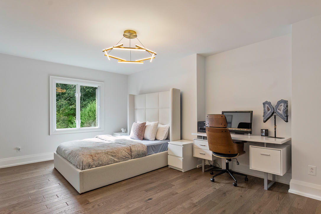 Modern bedroom with a bed, desk, and large window overlooking greenery