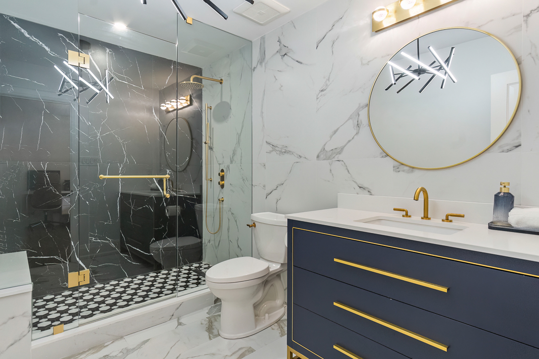 Modern bathroom with marble walls, glass shower, and navy vanity
