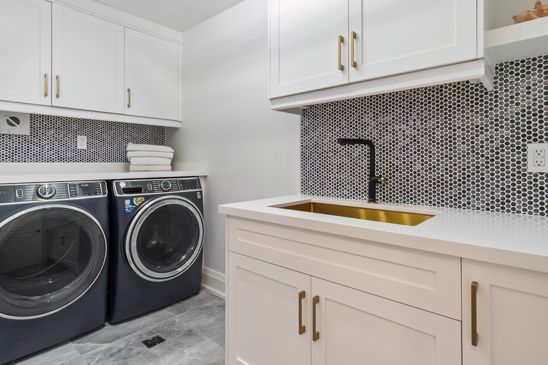 Modern laundry room with gray appliances and gold accents