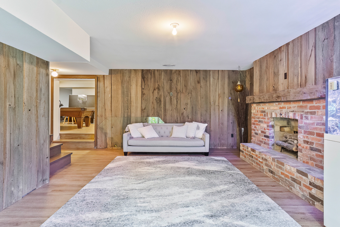 Cozy living room with wooden walls, a sofa, and a brick fireplace