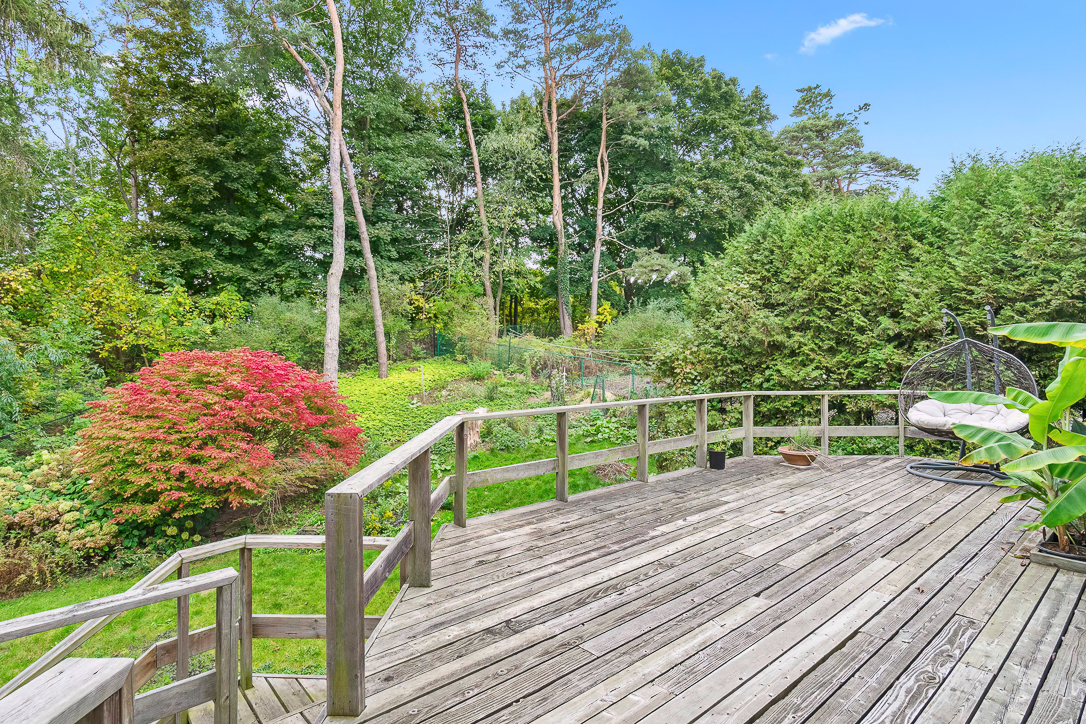 Wooden deck overlooking a lush garden with colorful foliage and trees