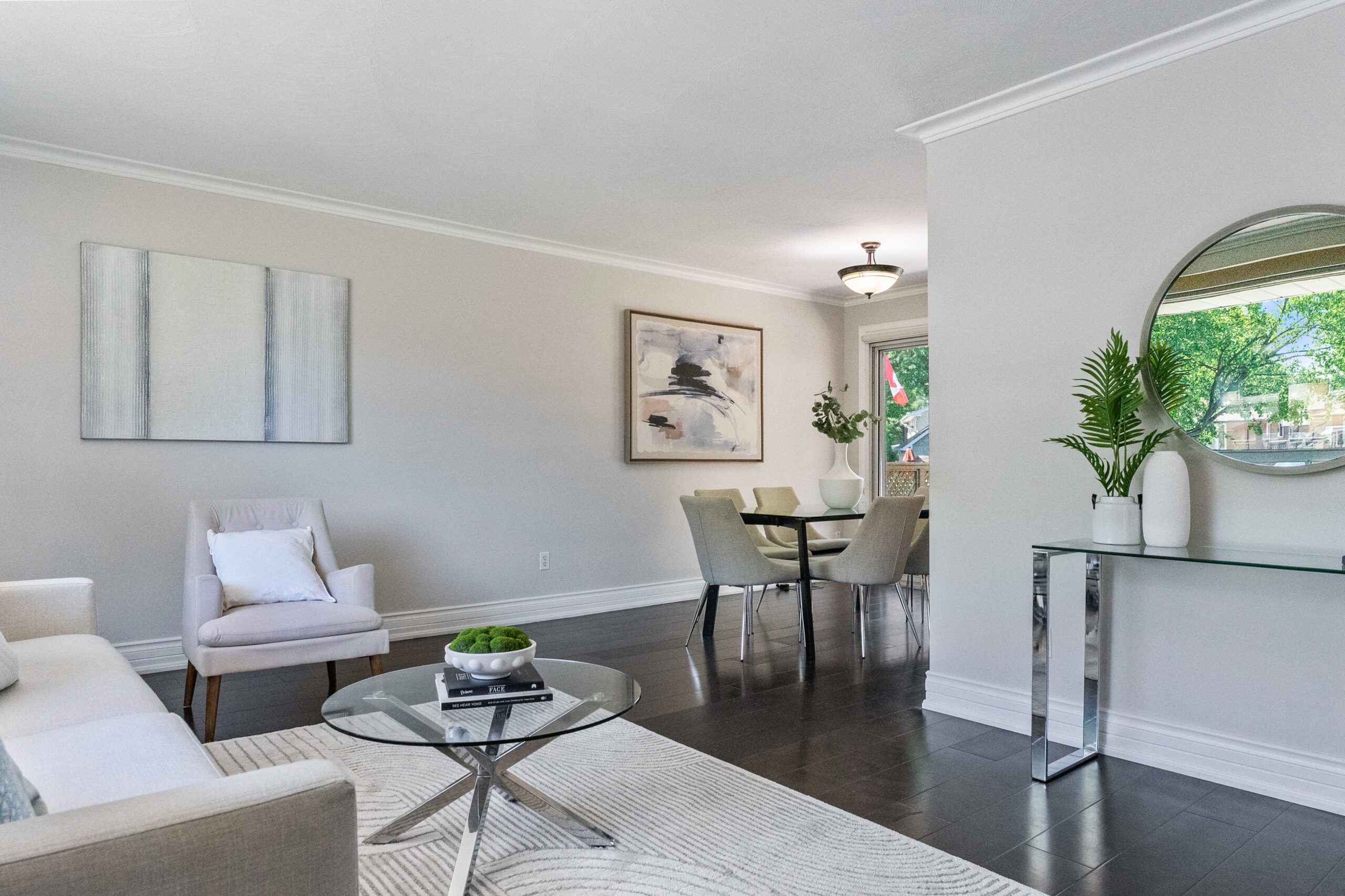 Modern living room with neutral colors, glass coffee table, and dining area.