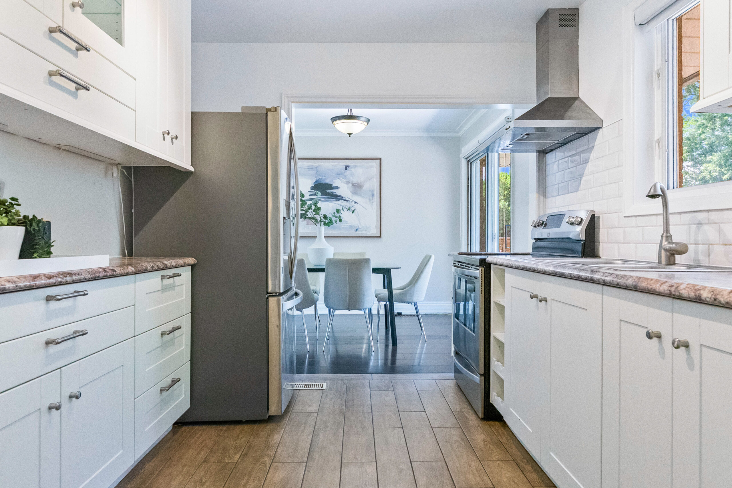 Modern kitchen with white cabinets and stainless steel appliances, leading to dining area