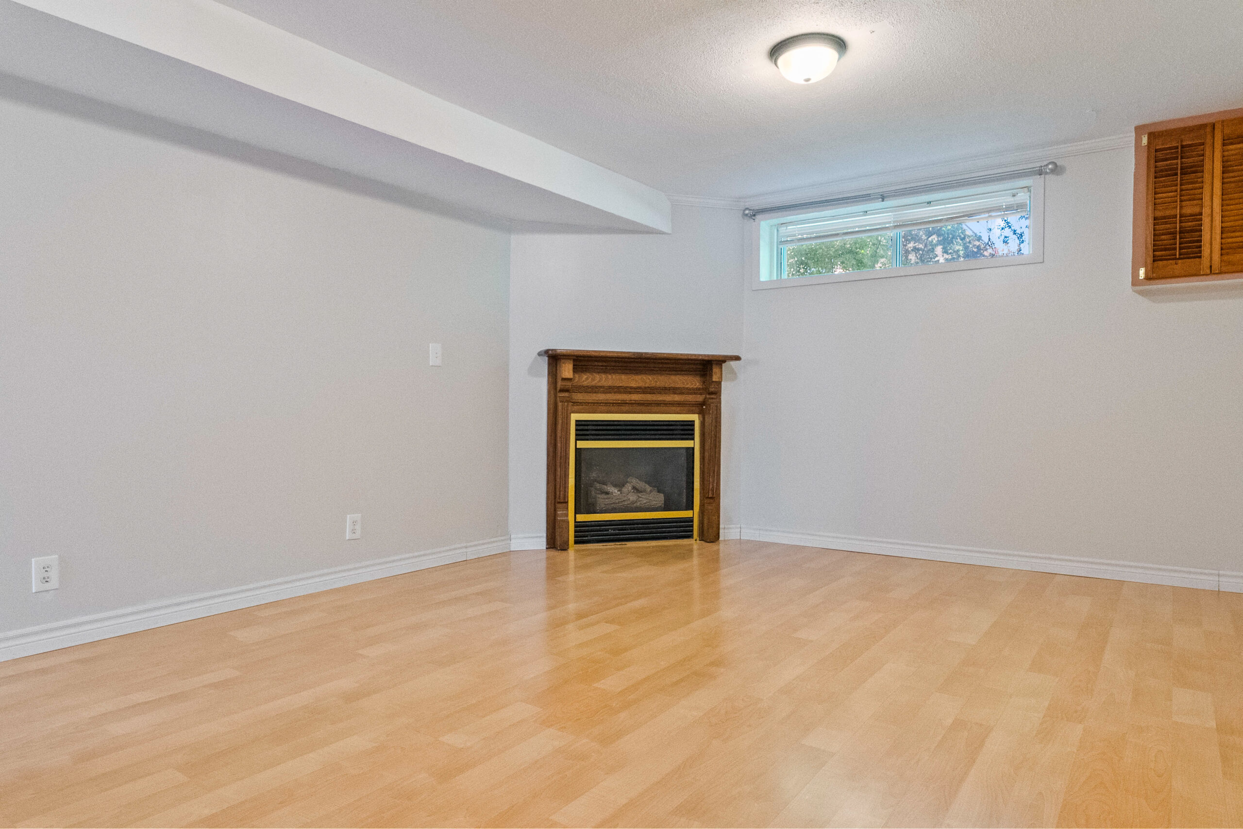Empty room with light wood flooring and a fireplace against a gray wall