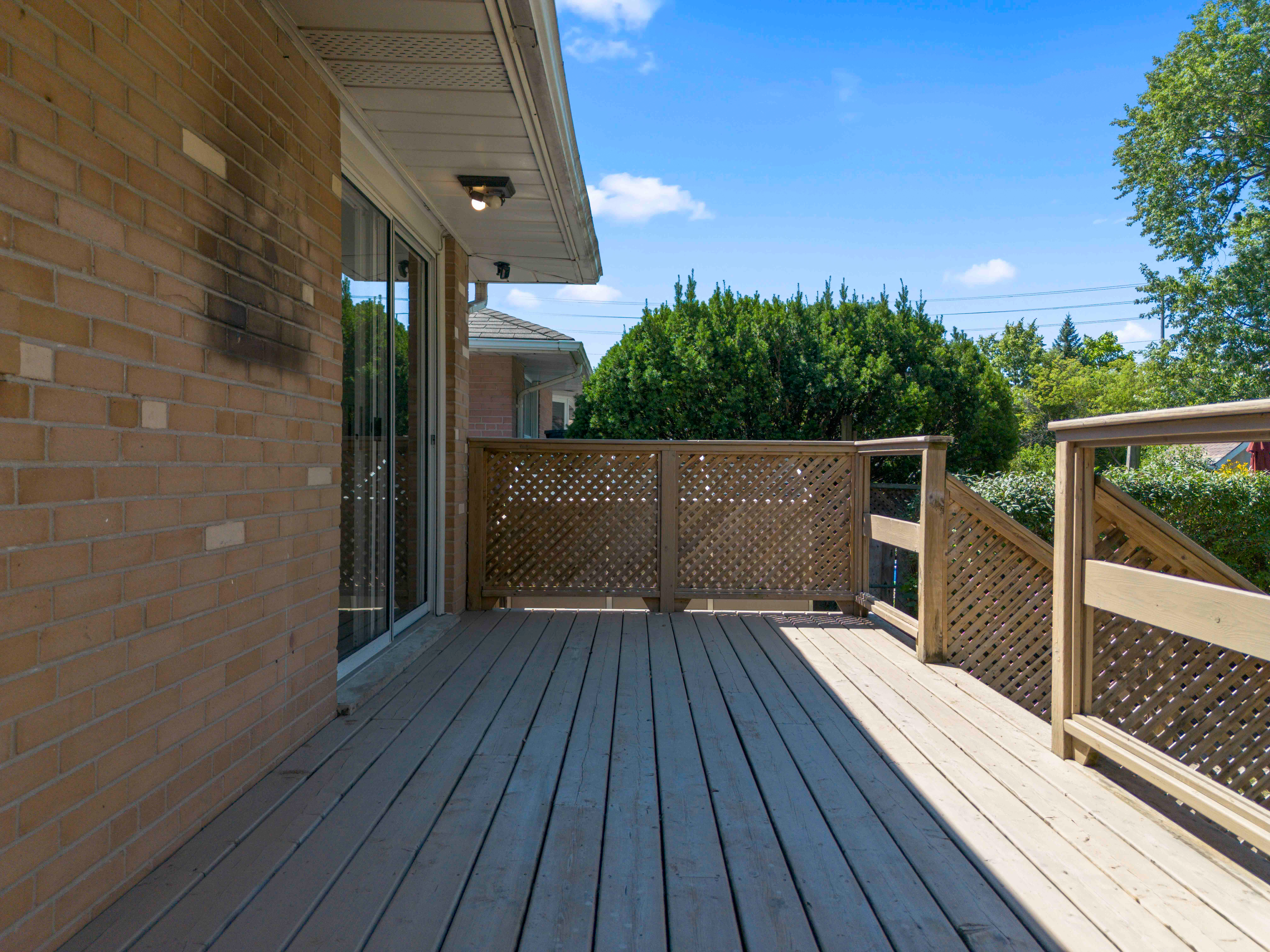 Wooden deck with lattice railing and blue sky in the background