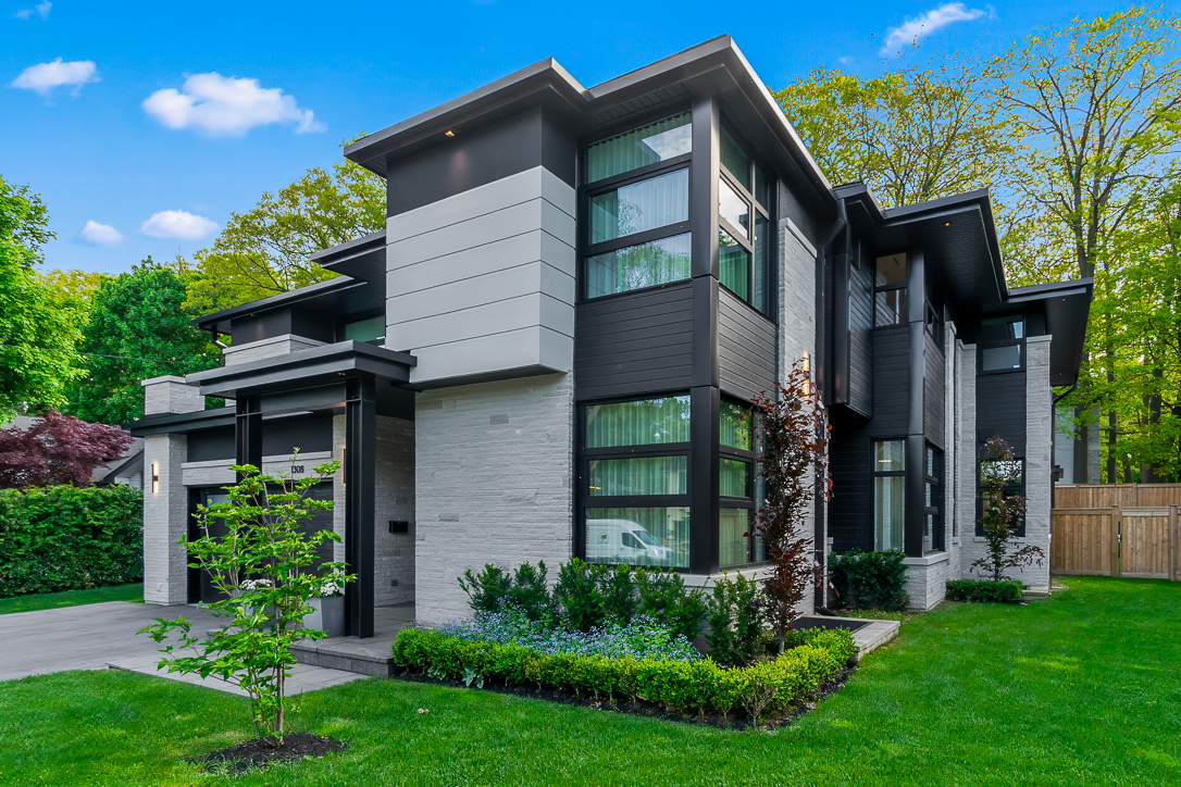 Modern two-story house with large windows and landscaped yard