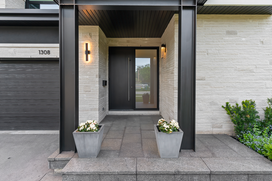 Modern entrance with black door, stone planters, and potted flowers