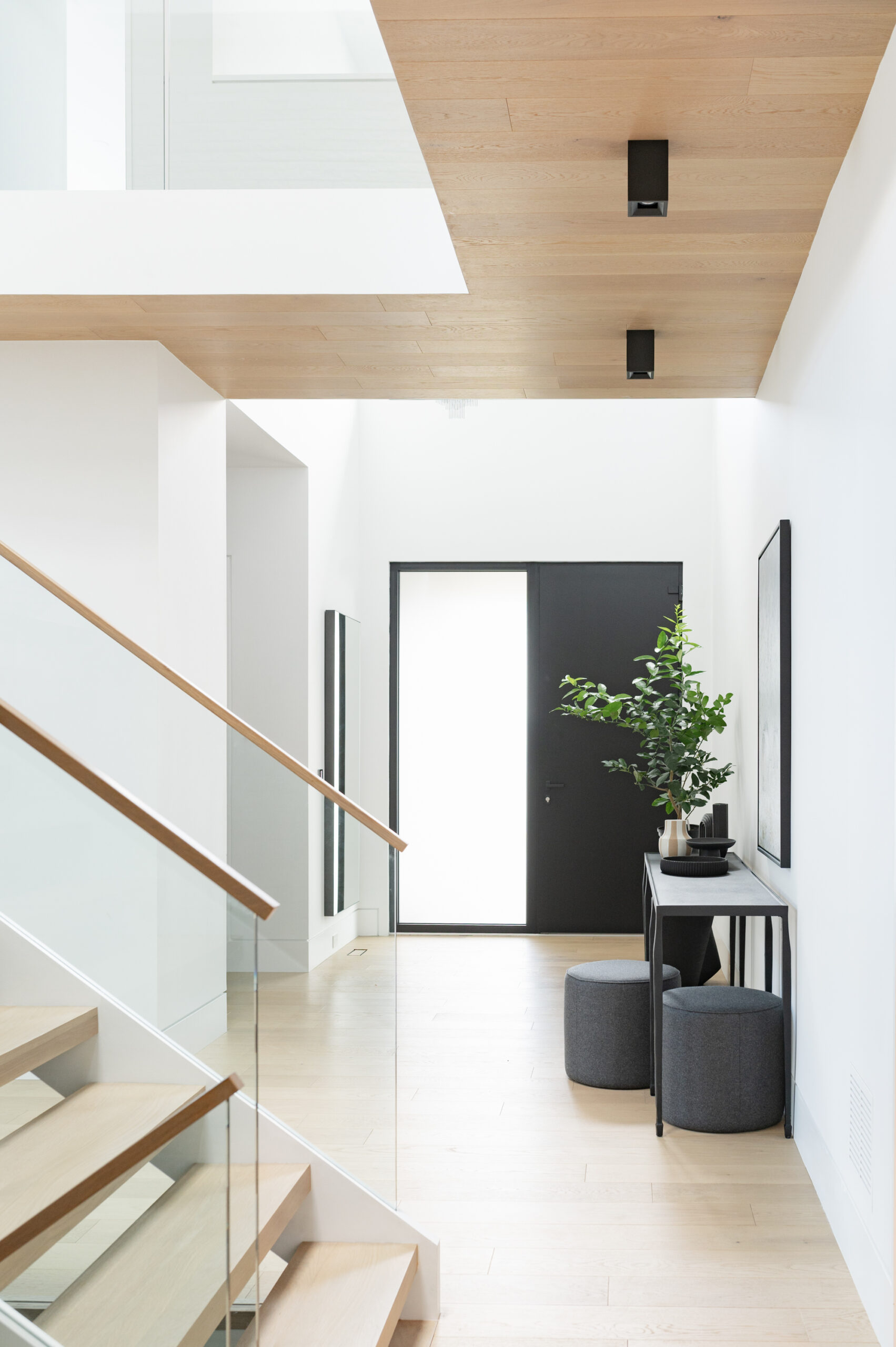 Modern hallway with wooden ceiling, glass railing, and black door