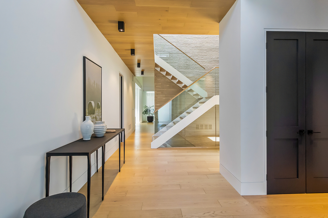 Modern hallway with wooden flooring and a staircase in the background
