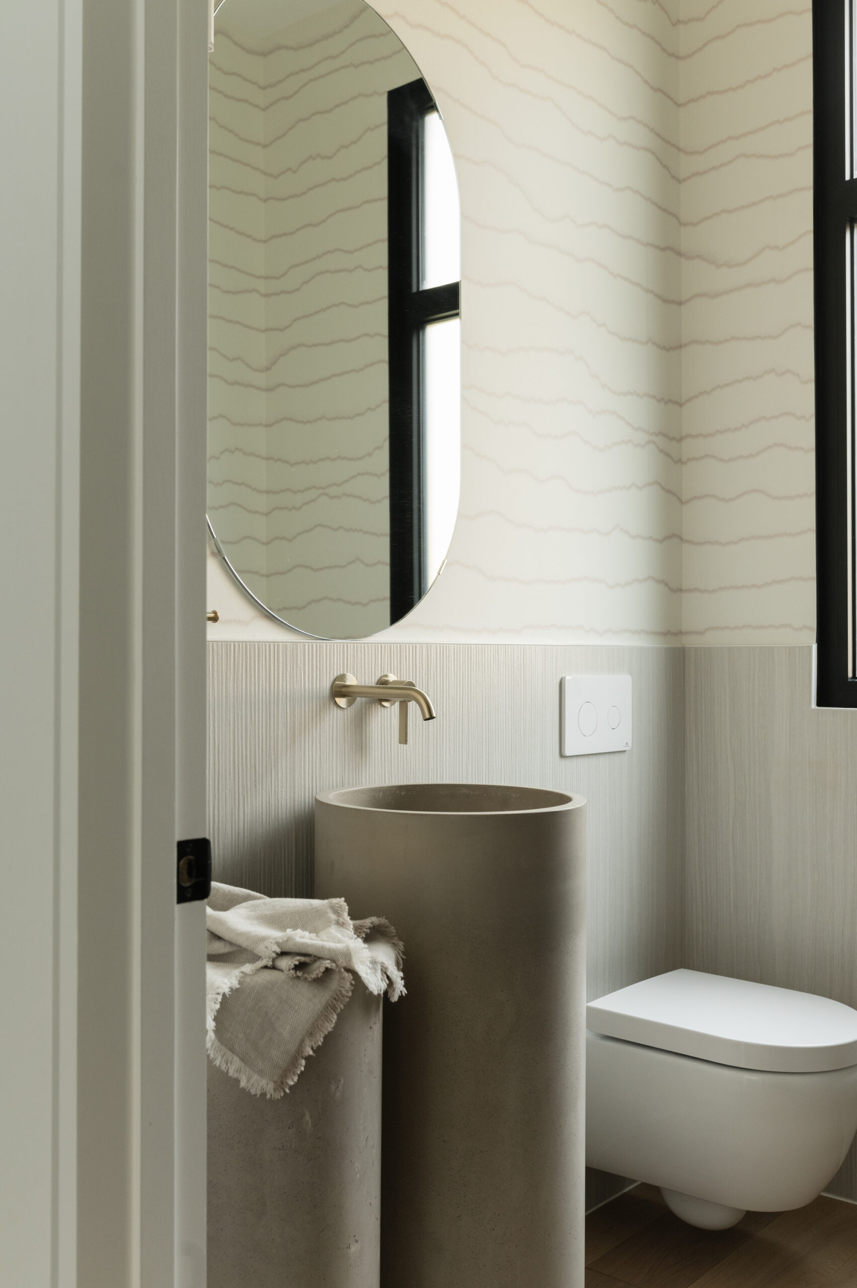Modern bathroom featuring a round mirror, cylindrical sink, and minimalist decor