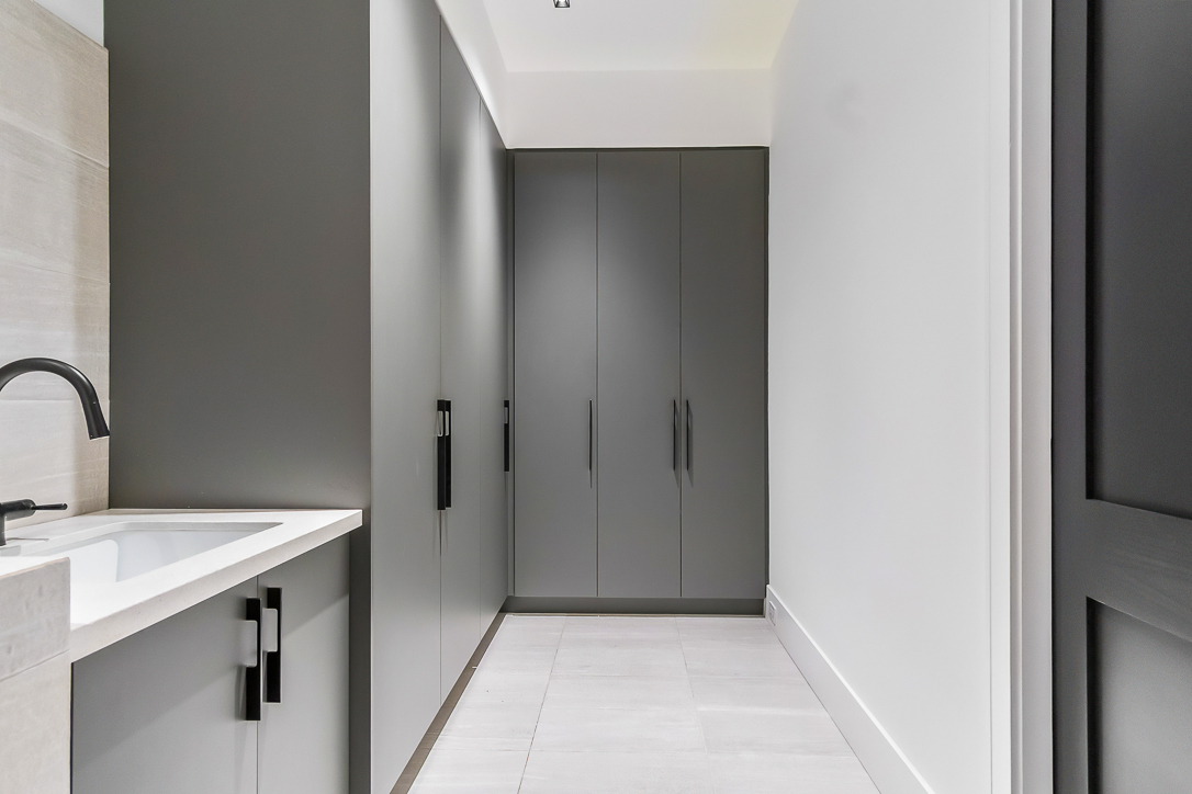 Modern hallway with gray cabinetry and white tile flooring