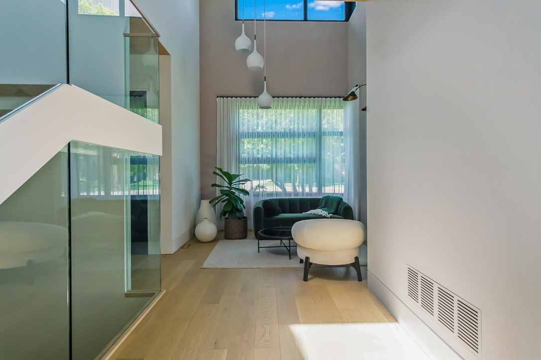 Modern hallway with a green couch, white chair, and large windows