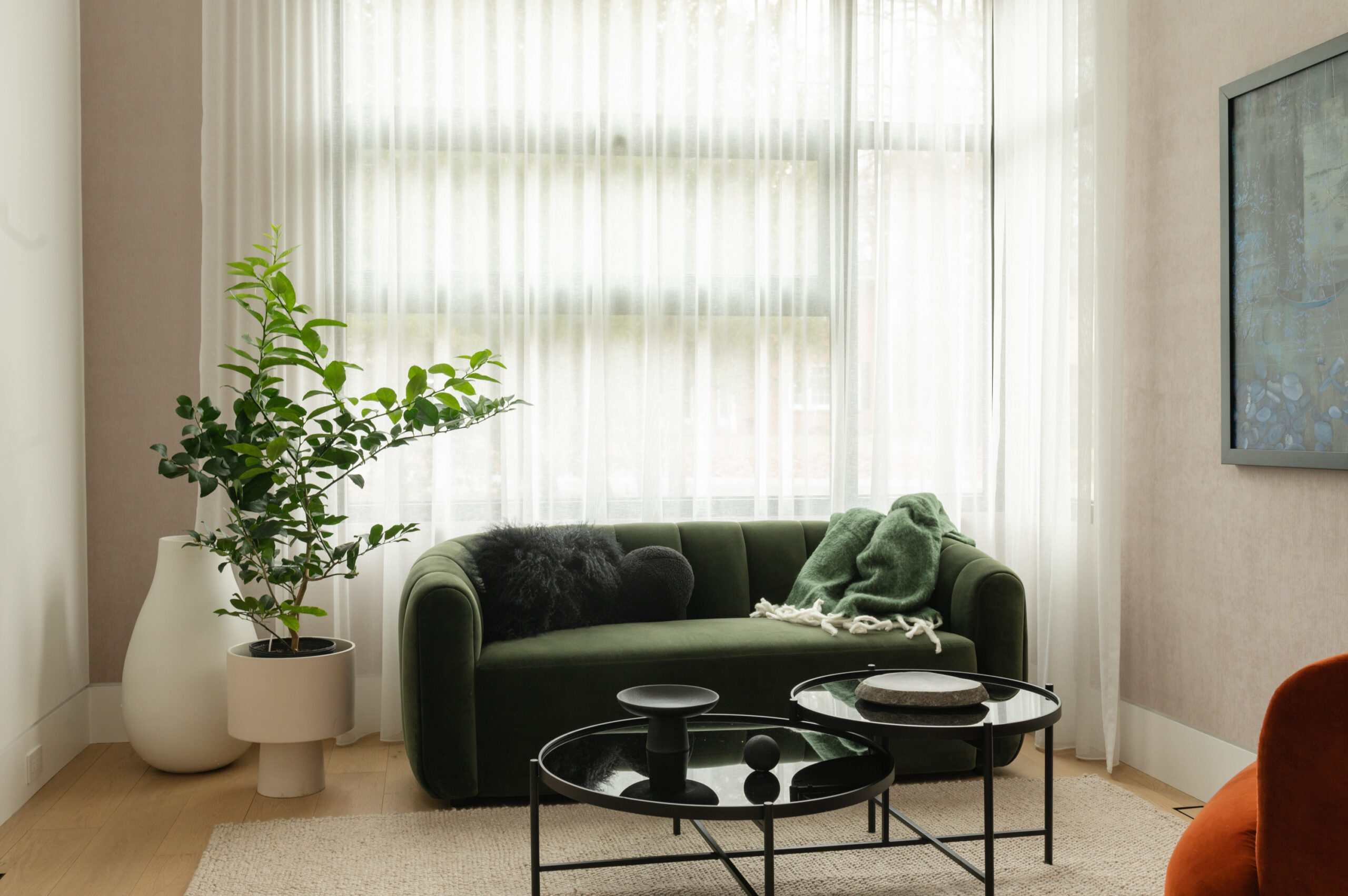 Cozy living room with a green sofa, glass tables, and large windows