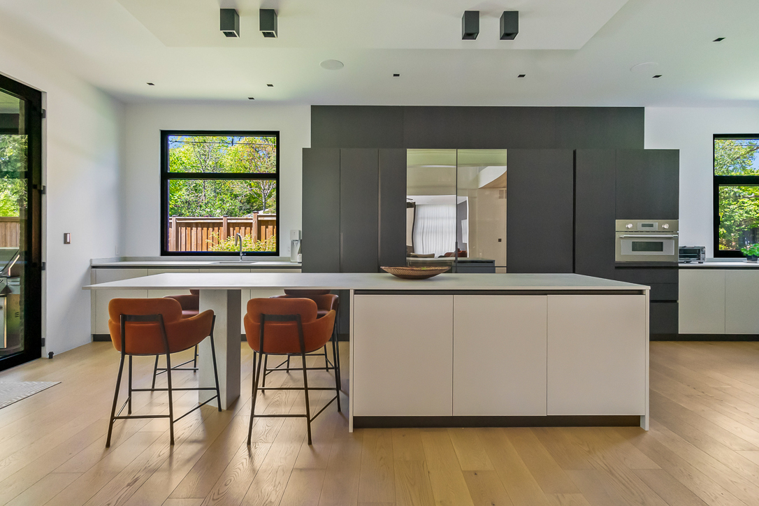 Modern kitchen with a large island, bar stools, and natural light.