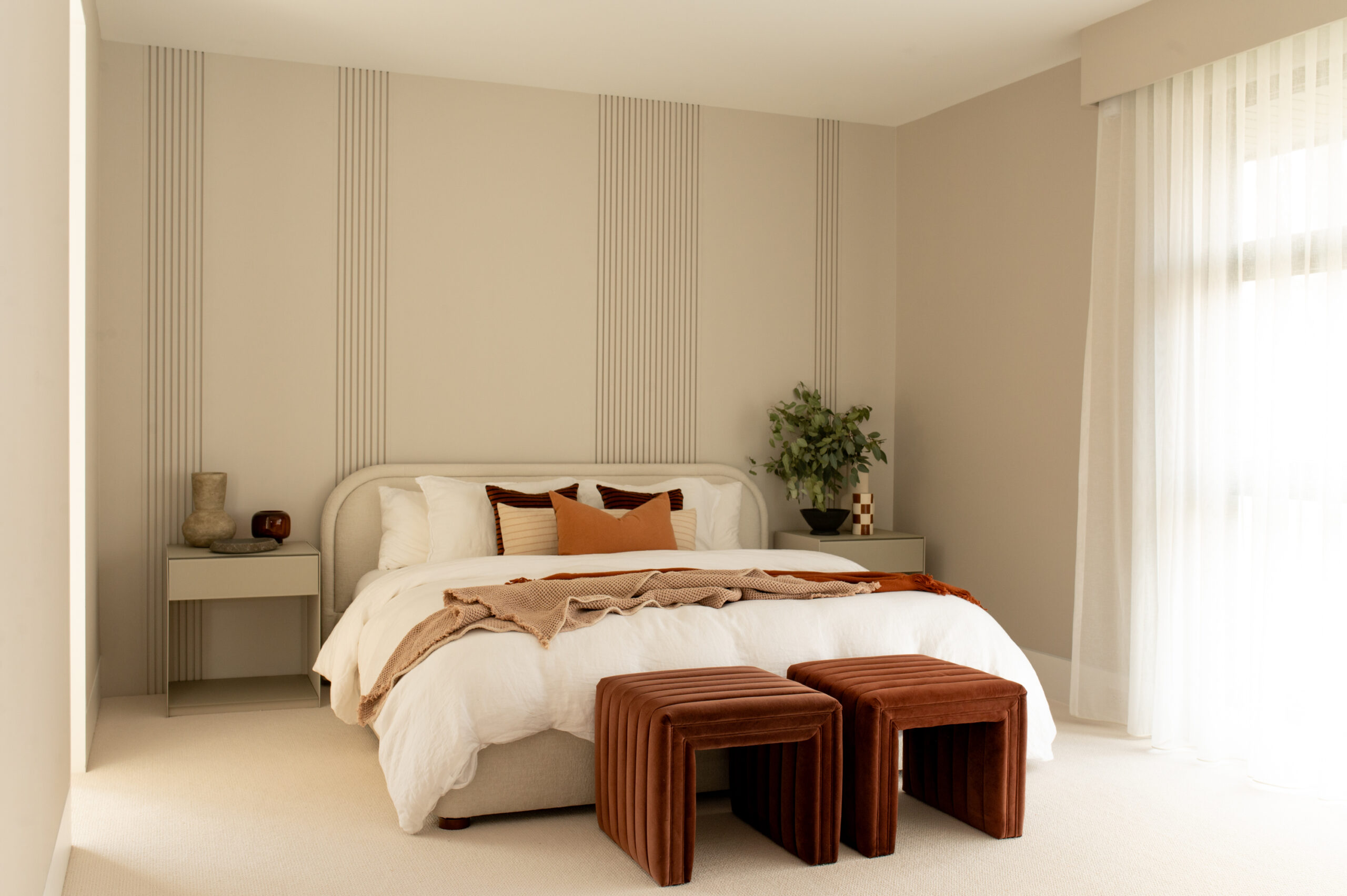 Cozy bedroom with a bed, decorative pillows, and wooden stools