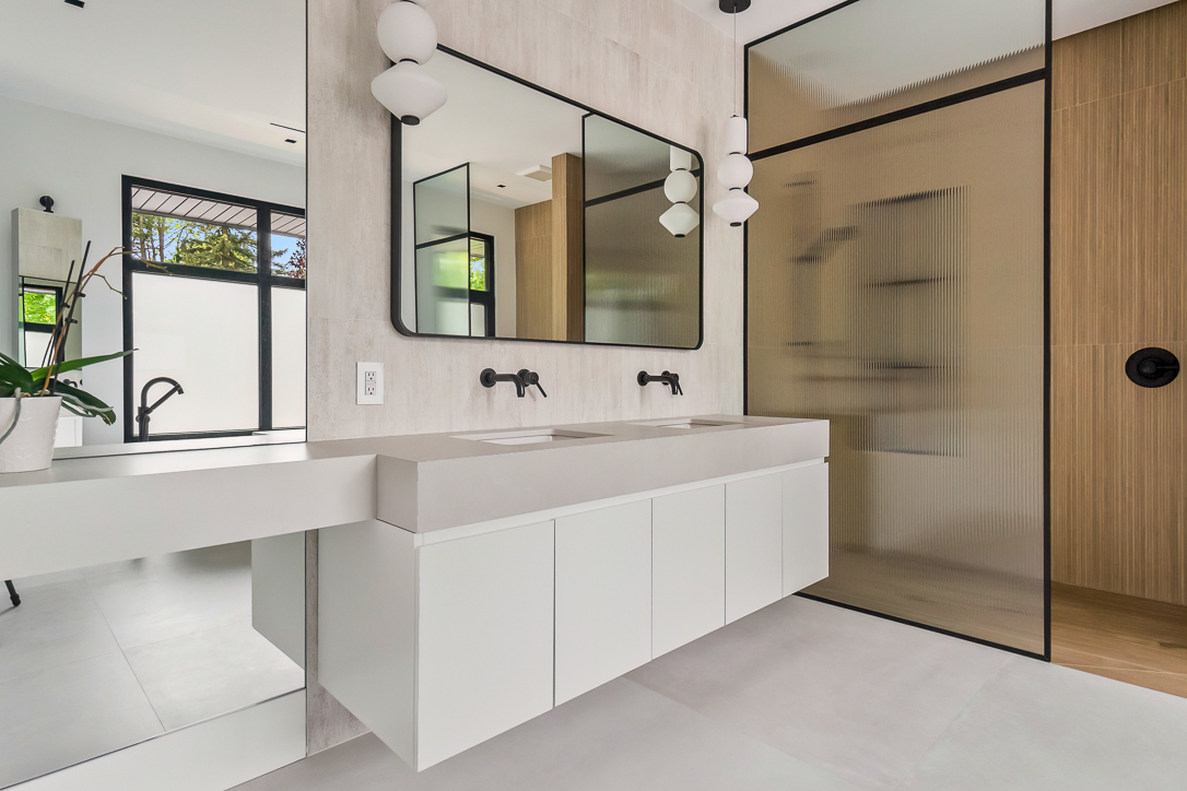 Modern bathroom with dual sinks, large mirrors, and glass shower enclosure
