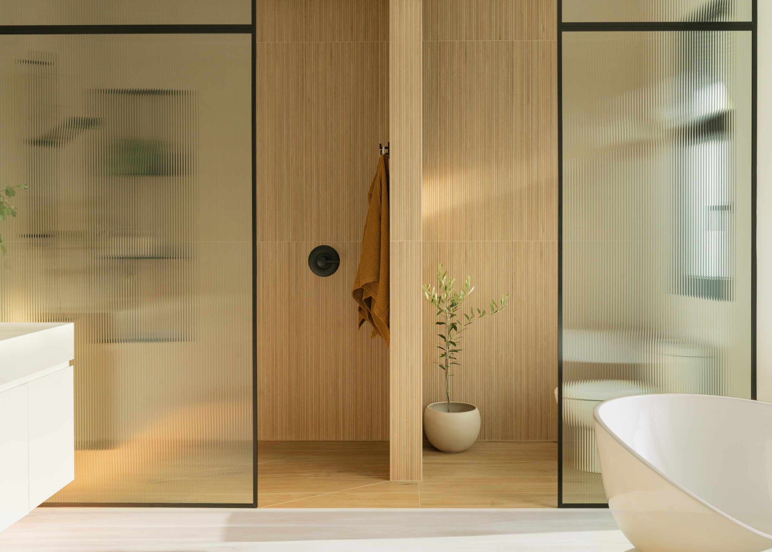 Modern bathroom with glass shower, wooden accents, and a freestanding tub