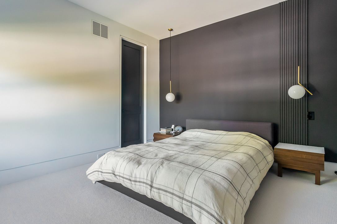 Modern bedroom with a dark accent wall and a cozy bed