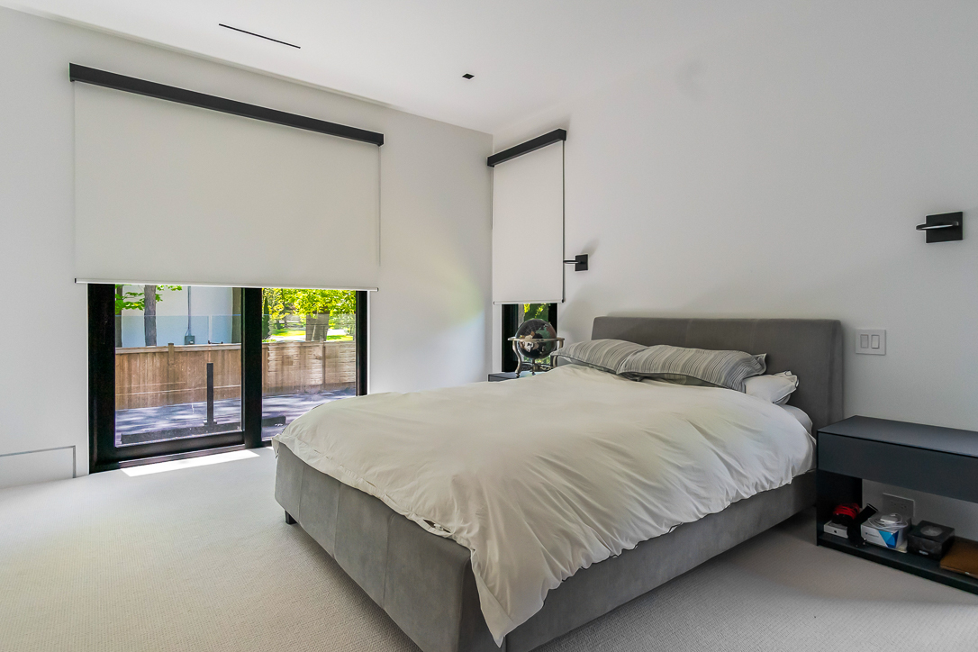 Modern bedroom with a gray bed and large windows.