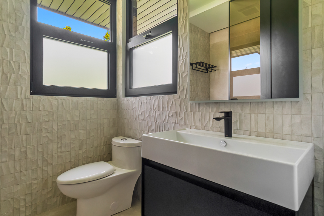 Modern bathroom featuring a white sink, black cabinetry, and large windows
