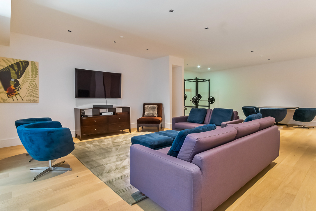 Modern living room with purple sofa, blue chairs, and TV setup