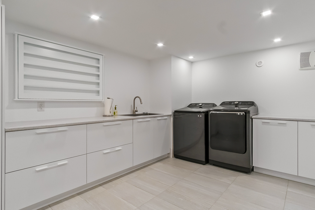 Modern laundry room with black appliances and white cabinetry