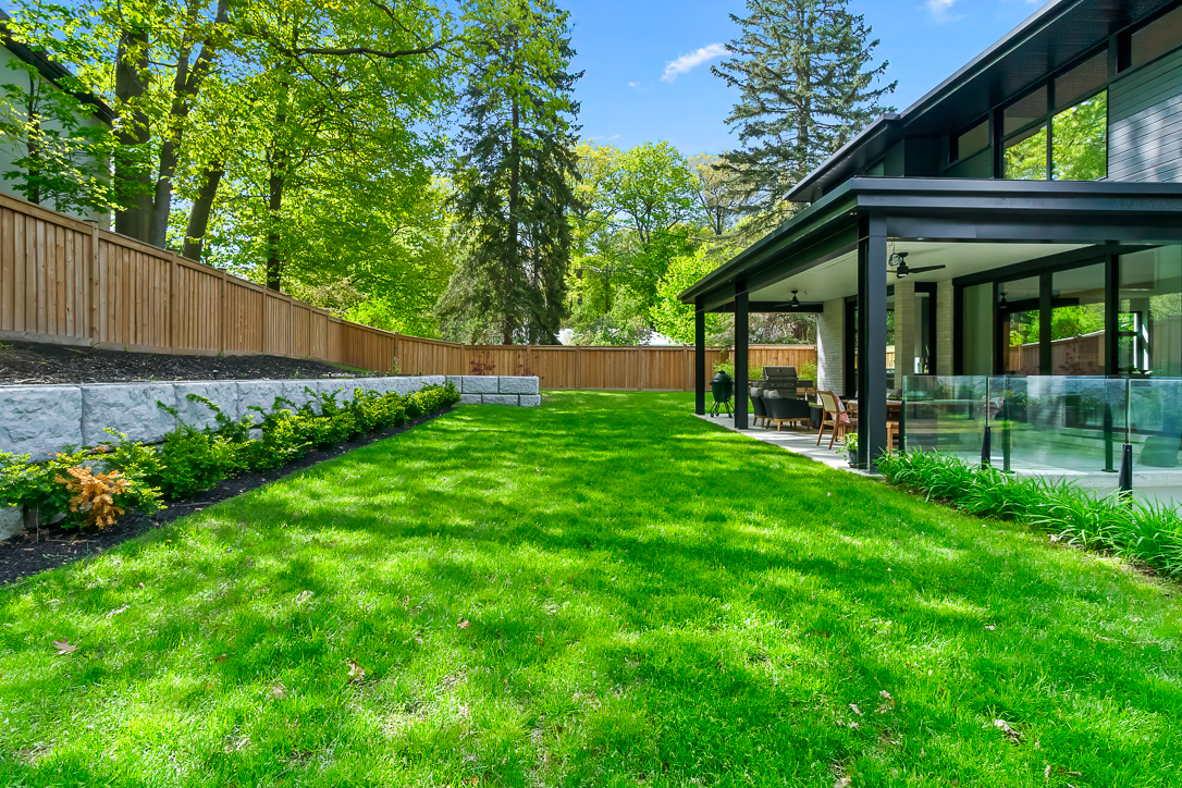 Lush green lawn with modern home and trees in the background