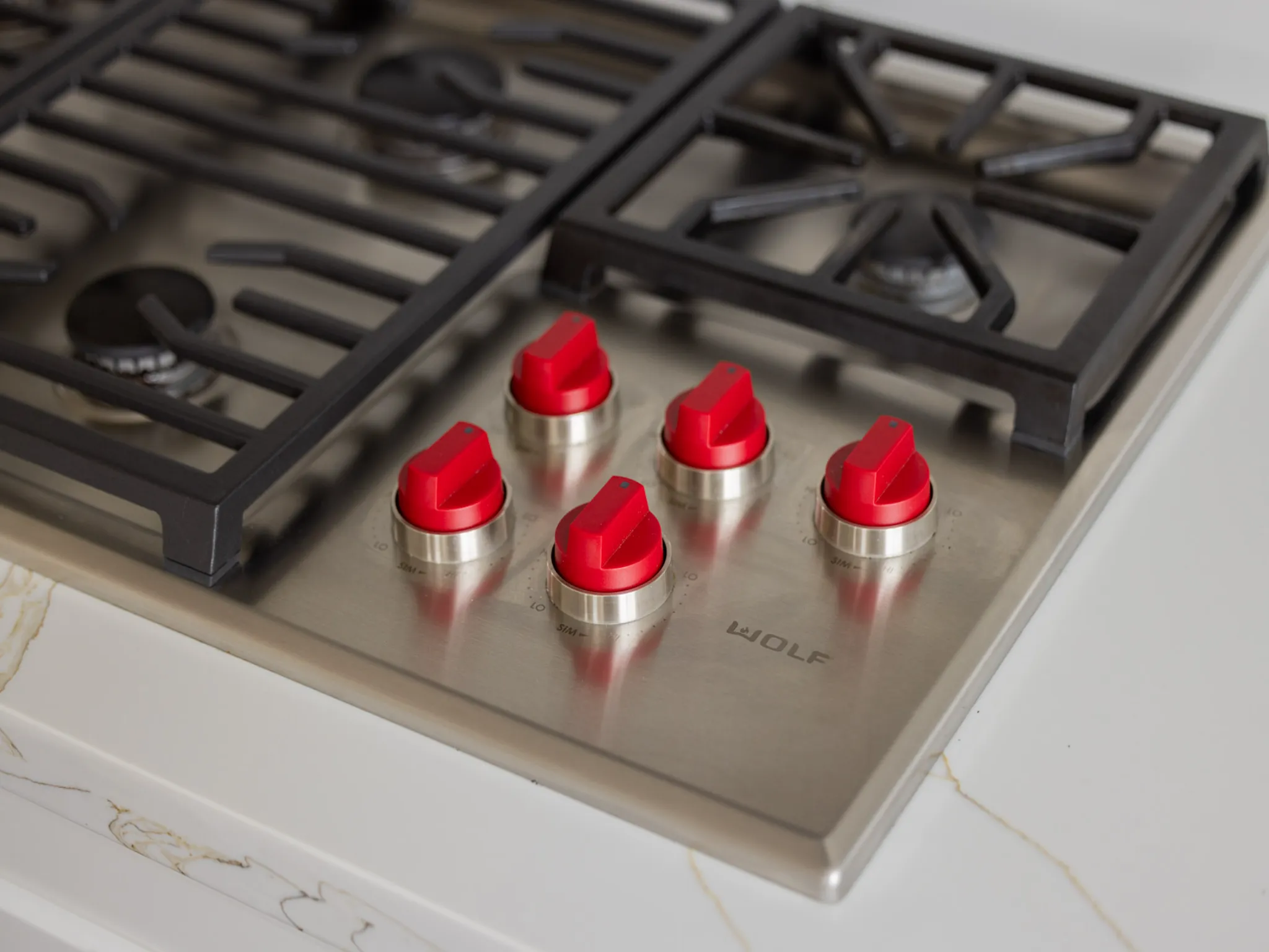 gas range top with black grills and red knobs