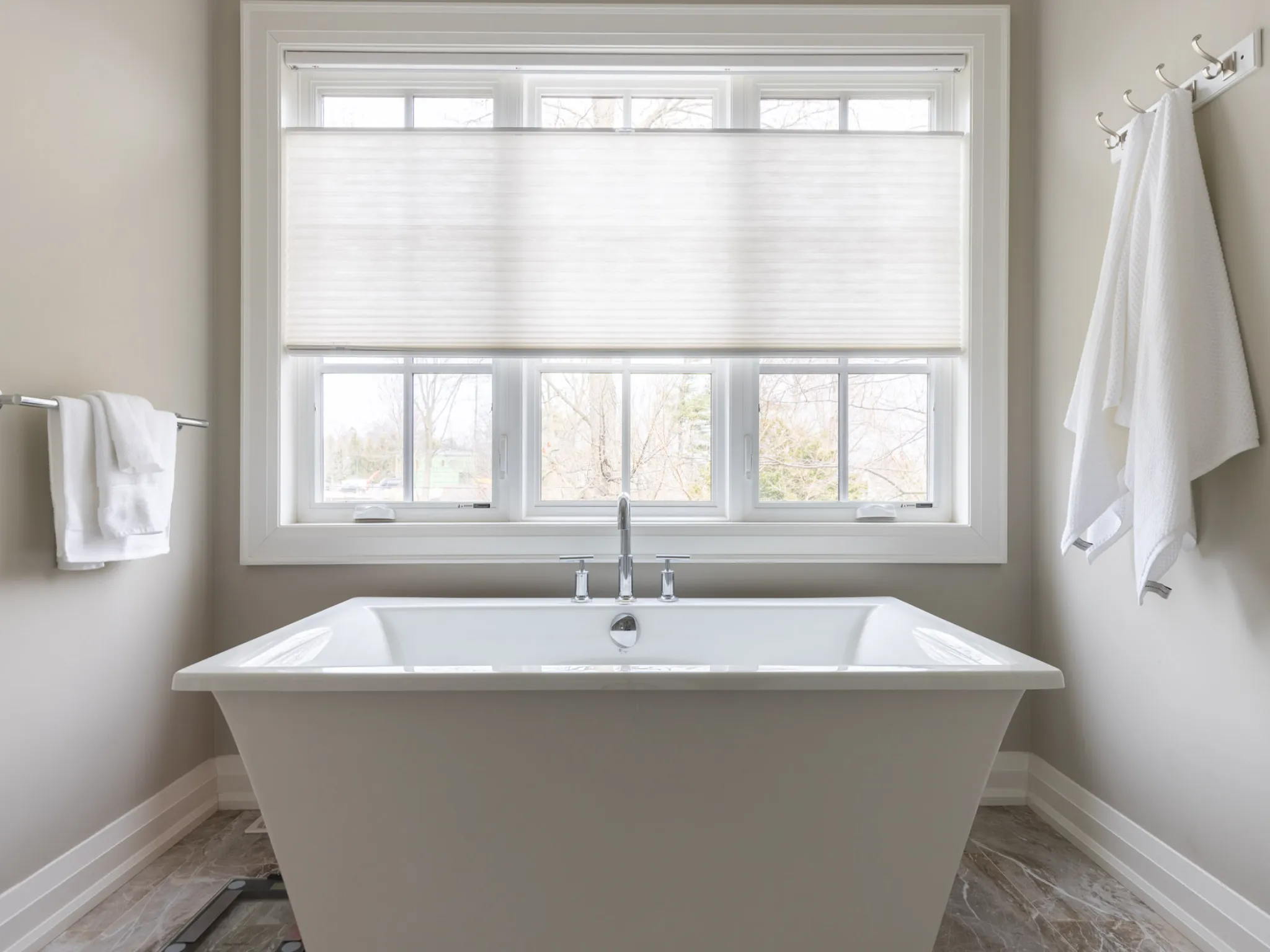 big white soaker tub with large white window behind it