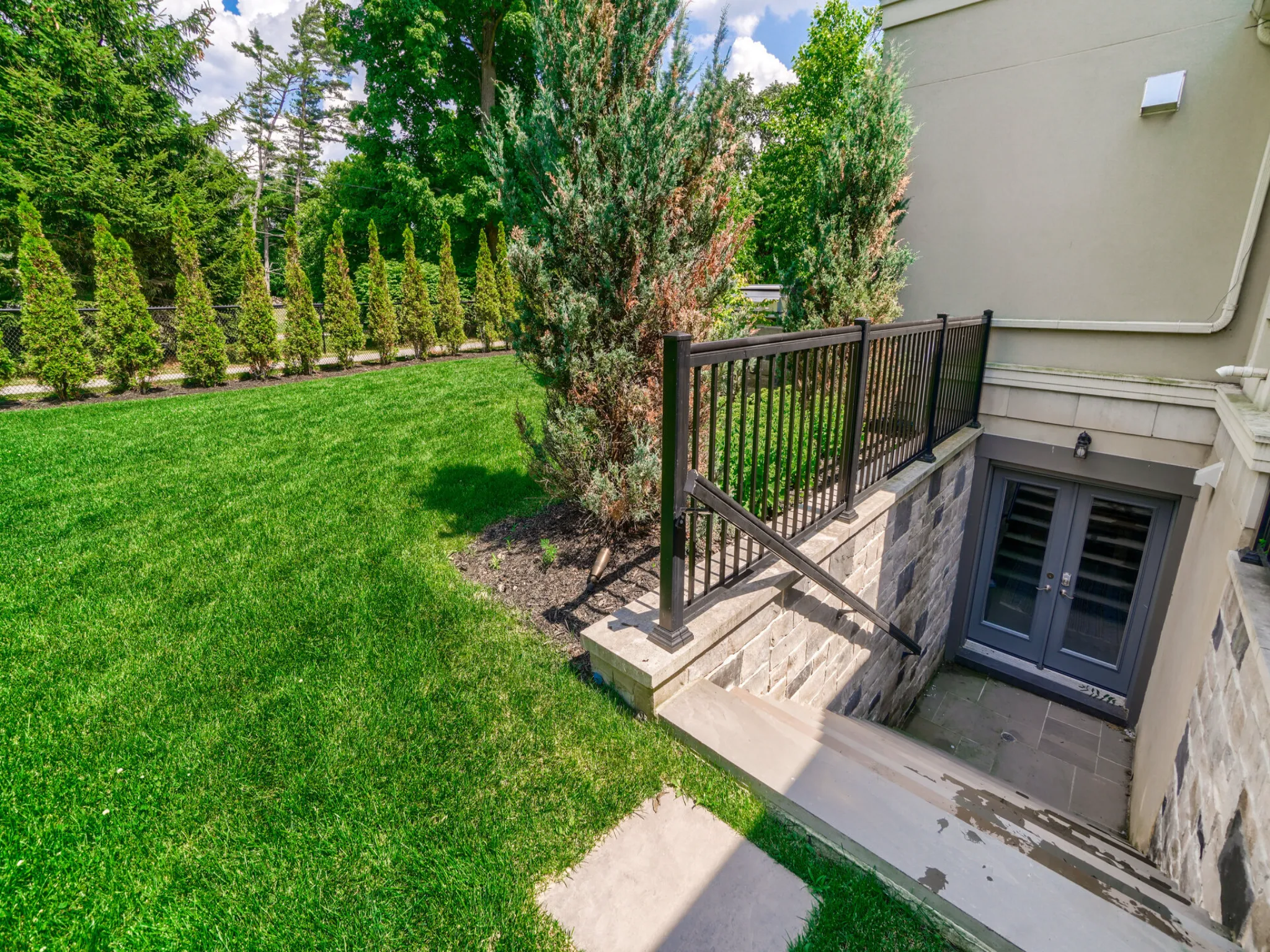 in the backyard, showing the landscaping and staircase down to the backyard.