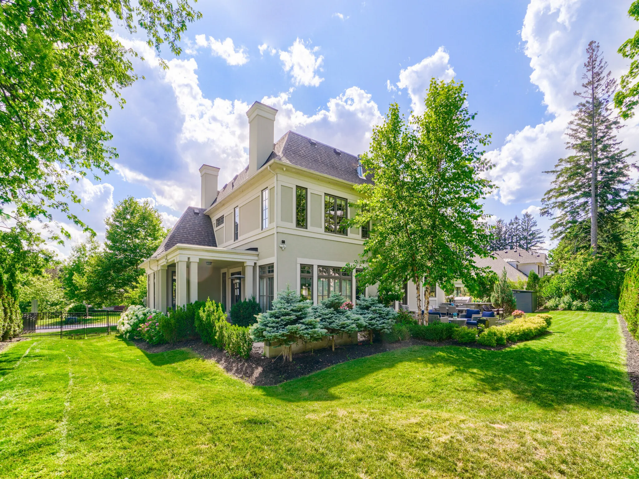 exterior of the property with large mature trees and beautiful plantings