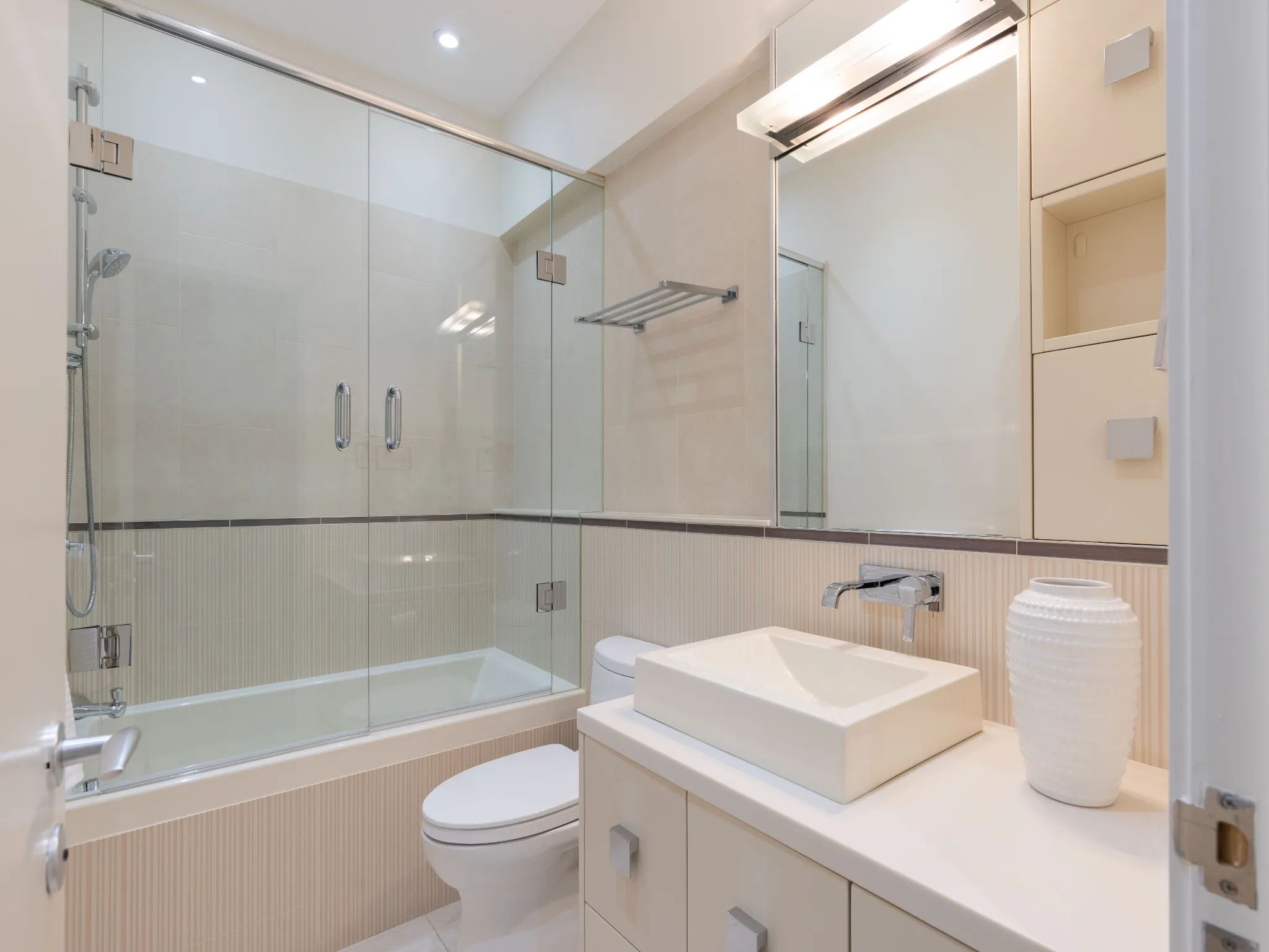 lower level bathroom with tub and glass enclosure, large vanity with sink