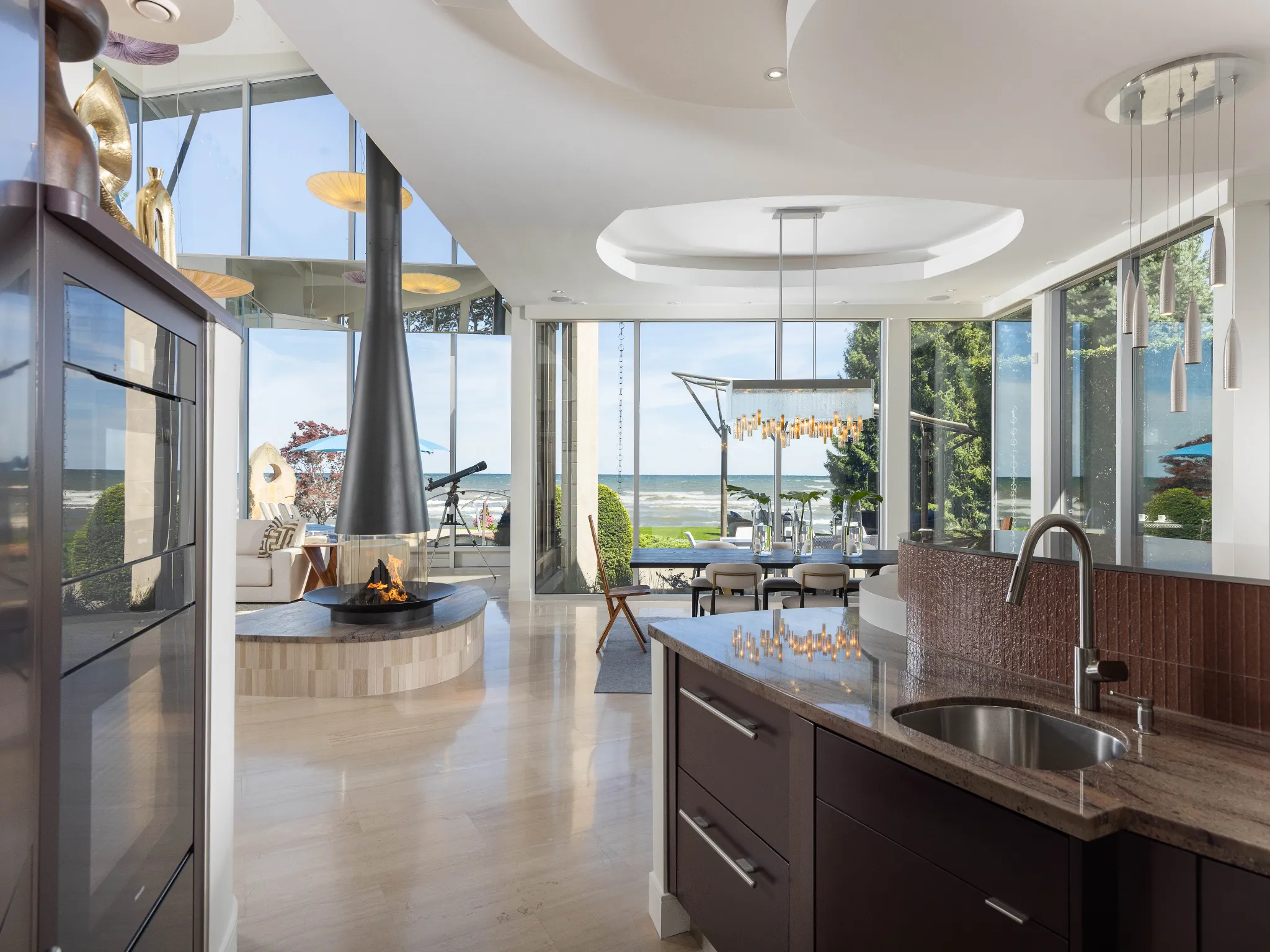 views from the kitchen overlooking the dining and in the background is the waves in the lake. luxurious sculptural fireplace