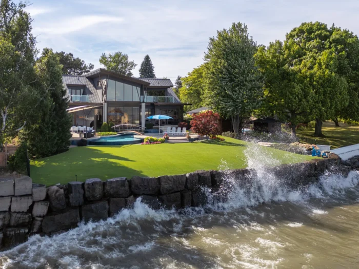 exterior of a modern lakefront home with water splashing on seawall