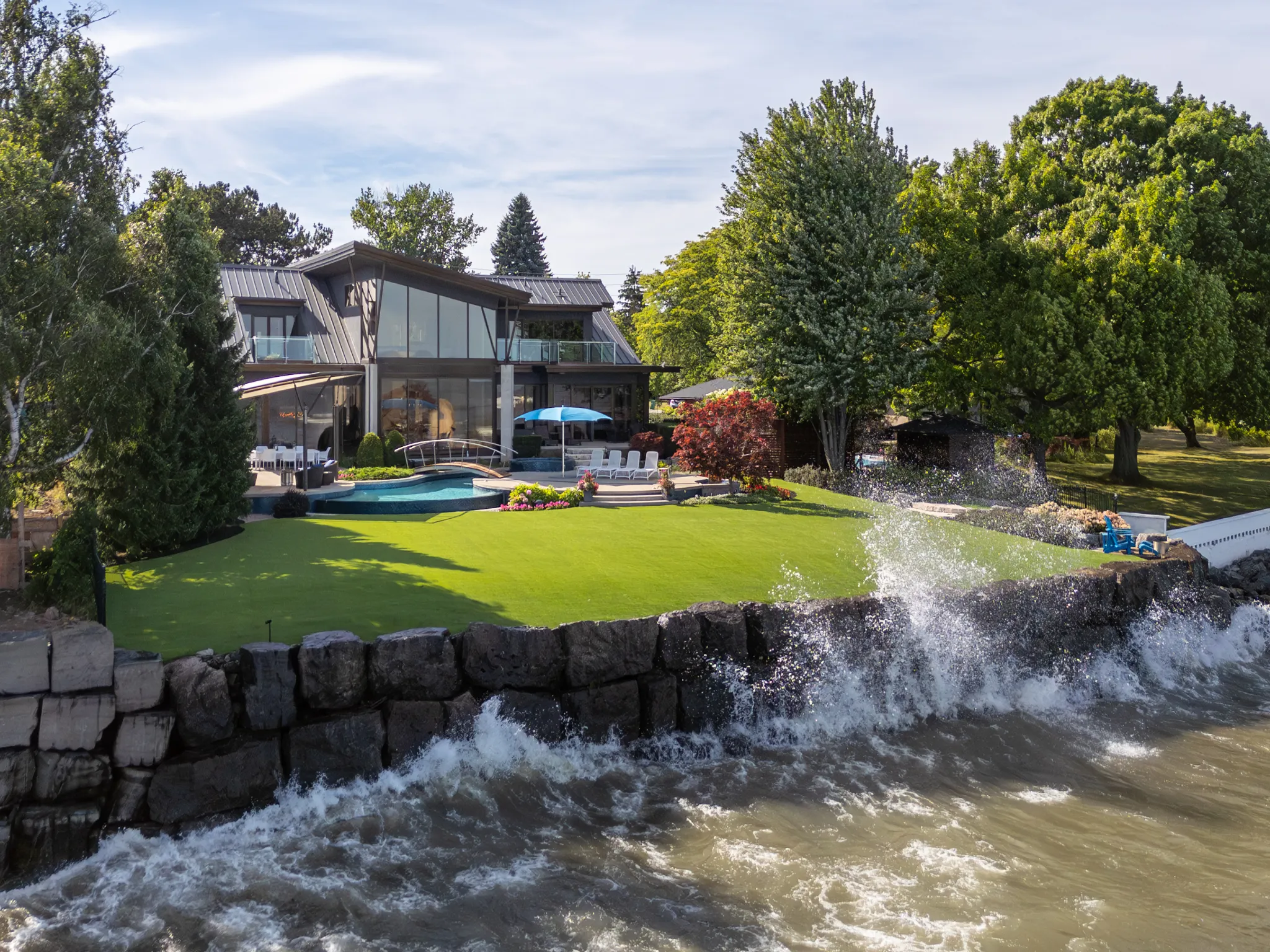 exterior of a modern lakefront home with water splashing on seawall