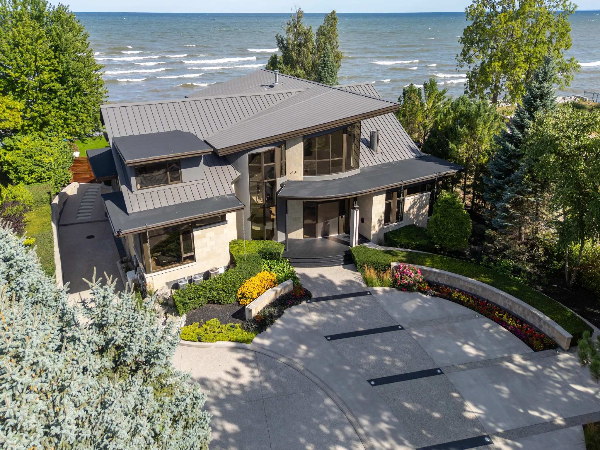 lakefront modern home with metal roof and mature trees