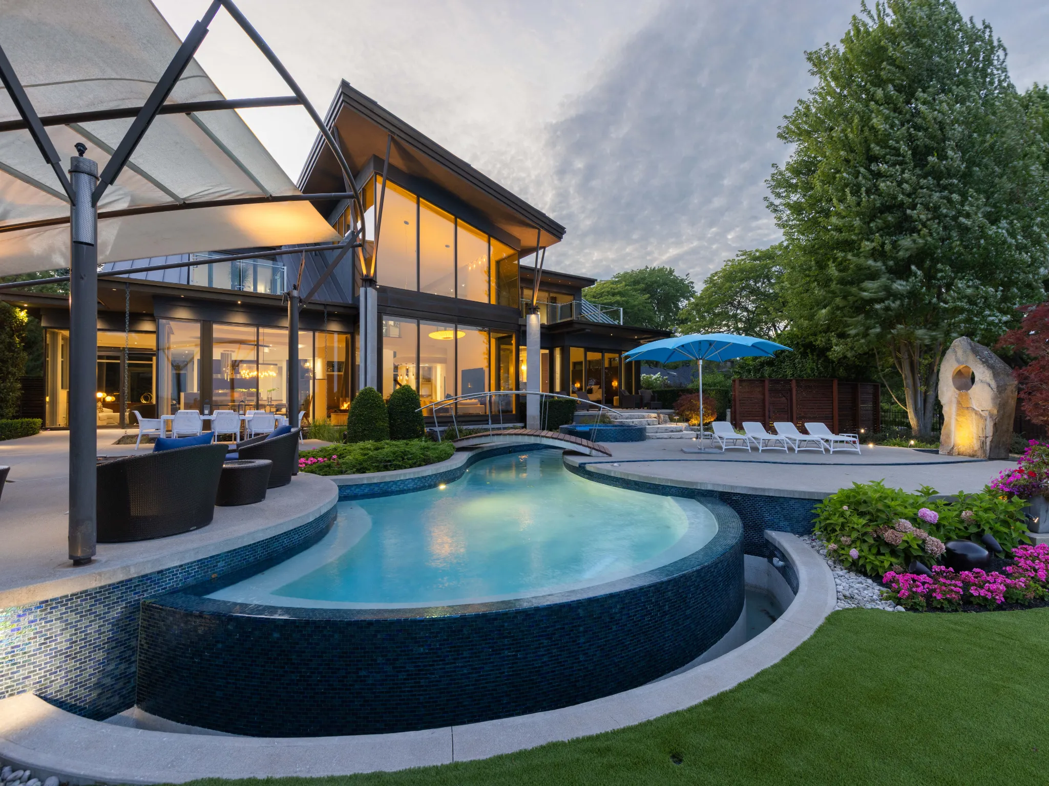 backyard photo with a pool and modern home with lots of beautiful landscaping