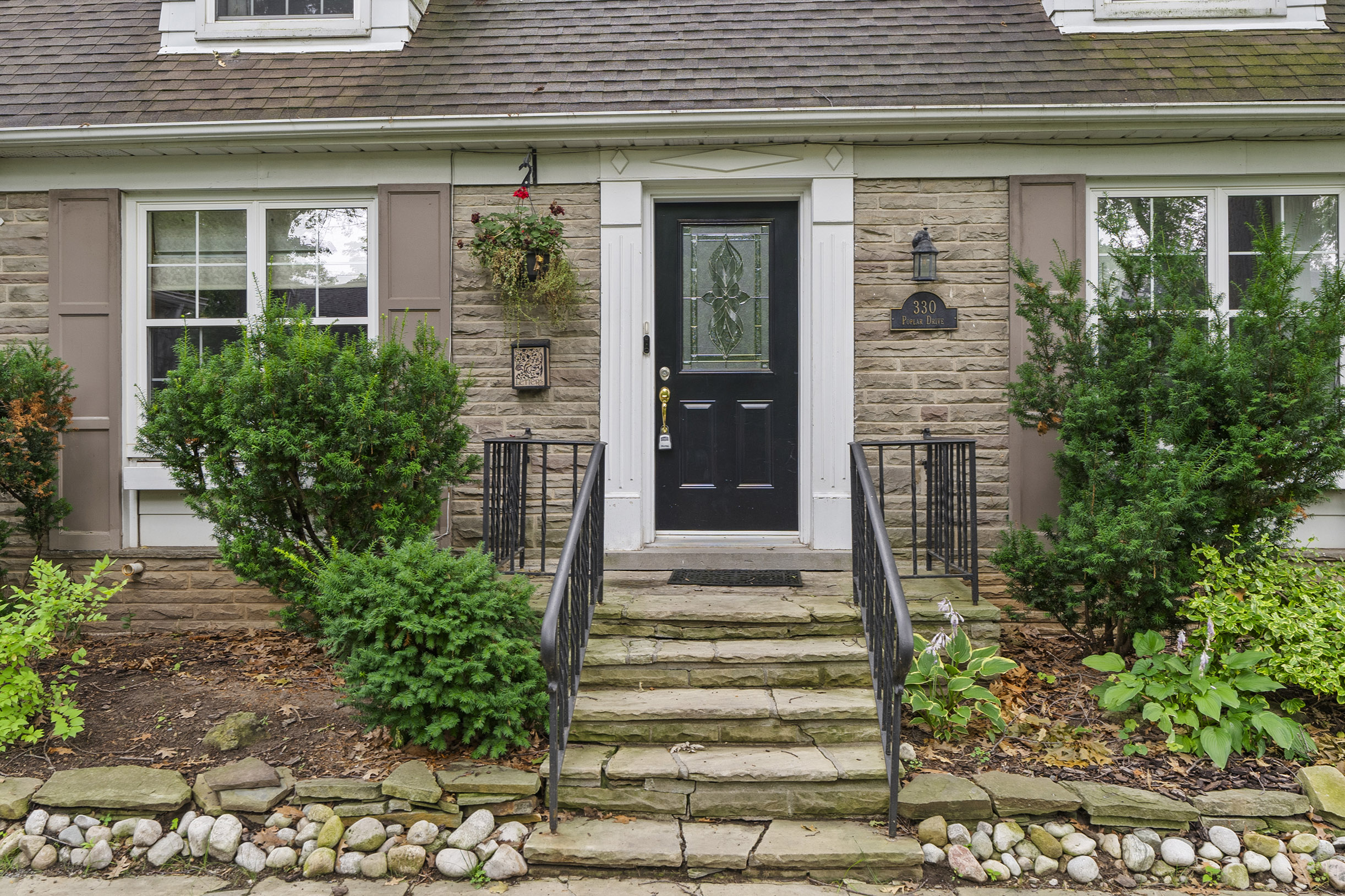 Front entrance of a house with stone steps and green landscaping
